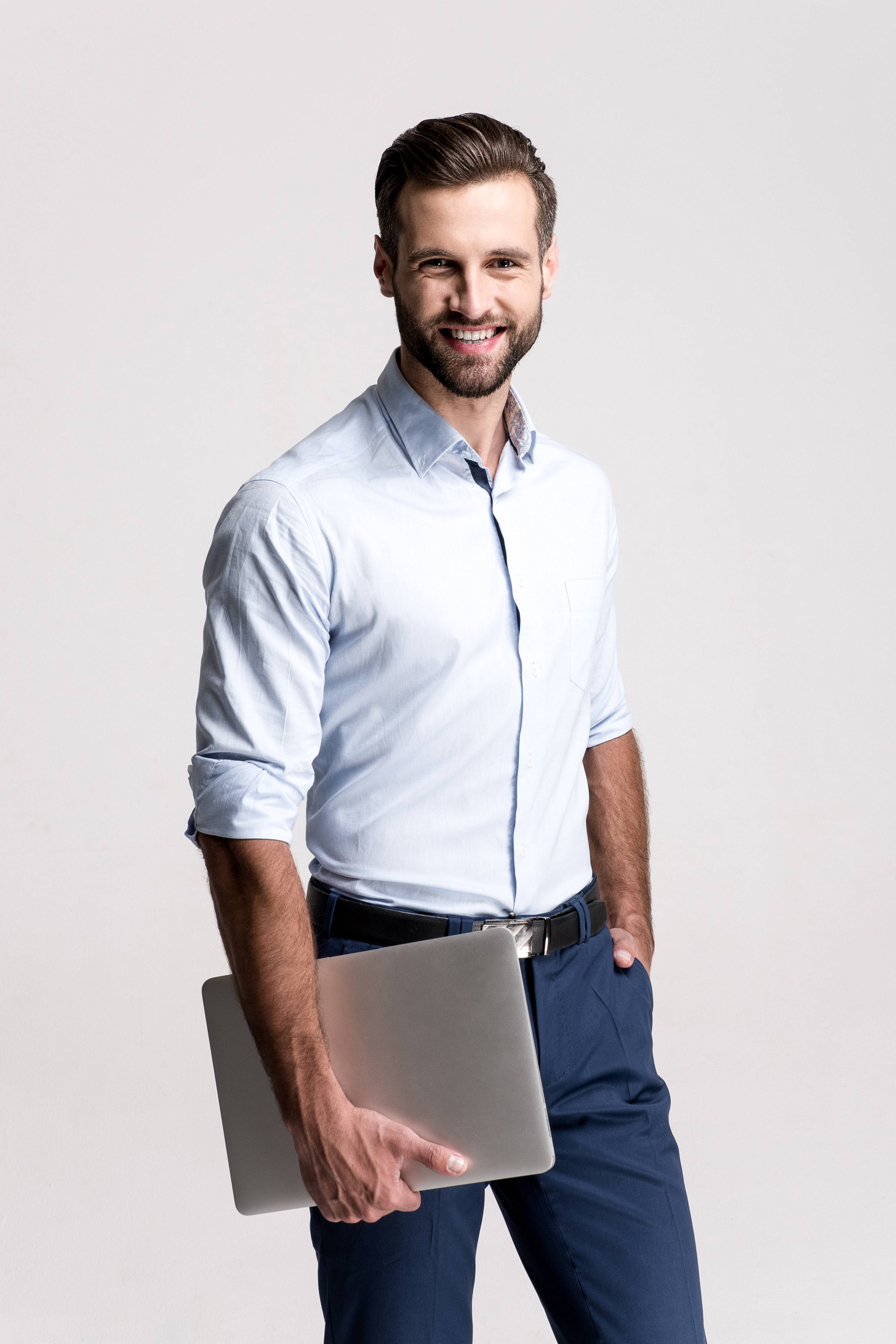 Successful at his work. Handsome young man holding his laptop and looking at camera with smile while standing against white background. contrat-infogerance
